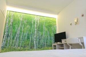 Un dormitorio con un ventanal grande, una cama, un escritorio con una computadora y un televisor.