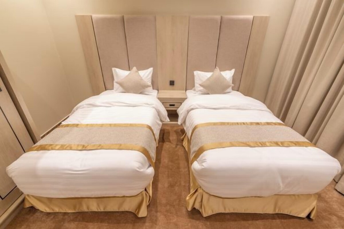 A double room with two beds, each with a headboard, a bedside table, and a small drawer.