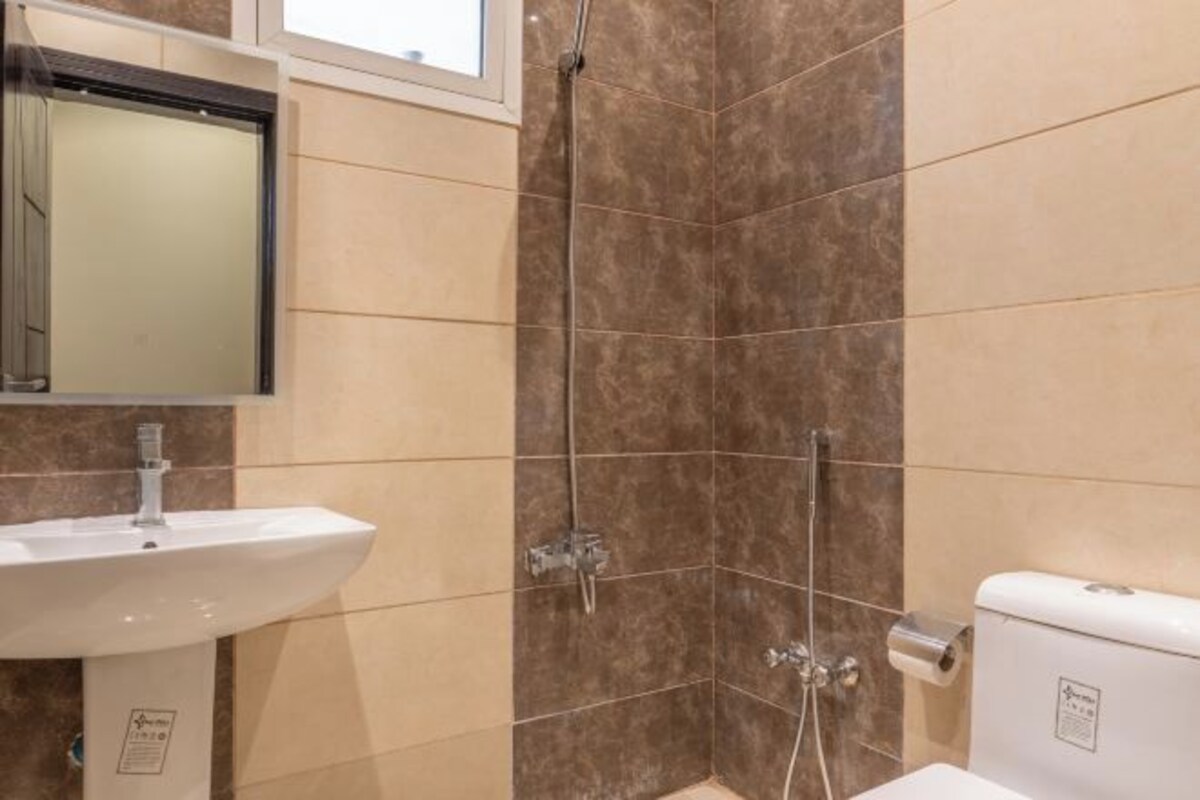 Une salle de bain équipée d’un lavabo, d’un miroir, d’une douche et de toilettes.