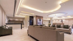A modern living room with a sectional sofa, a small coffee table, and a dining area with a counter and chairs. - Deyala Serviced Apartments 4 (Riyadh)