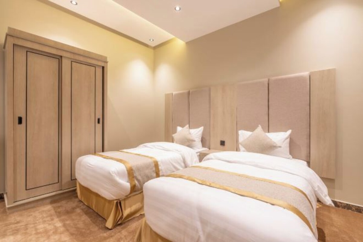 Une chambre d’hôtel avec deux lits, une armoire et une grande tête de lit.