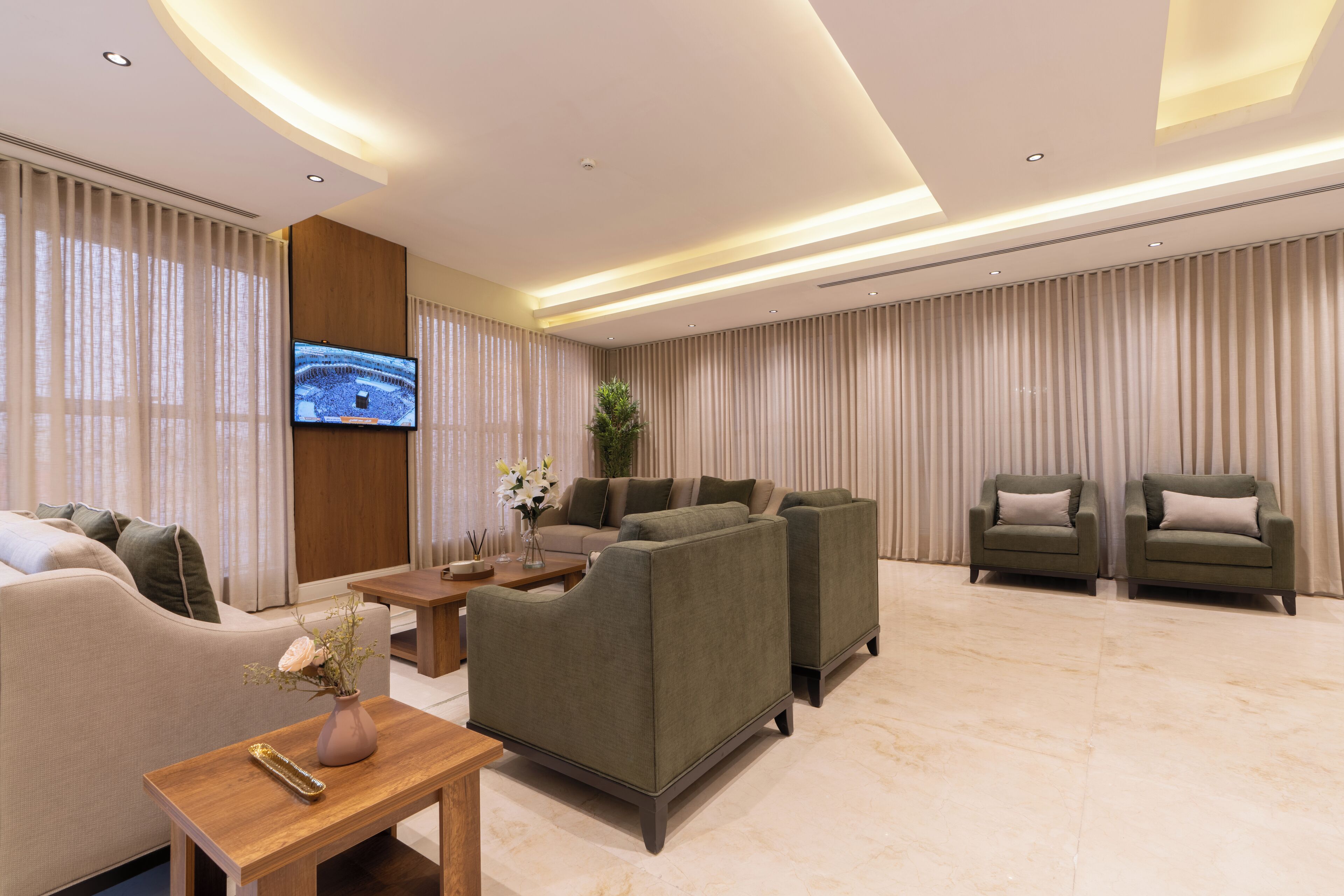 Una sala de estar moderna con un sofá, dos sillones, una mesa de centro y un televisor montado en la pared.