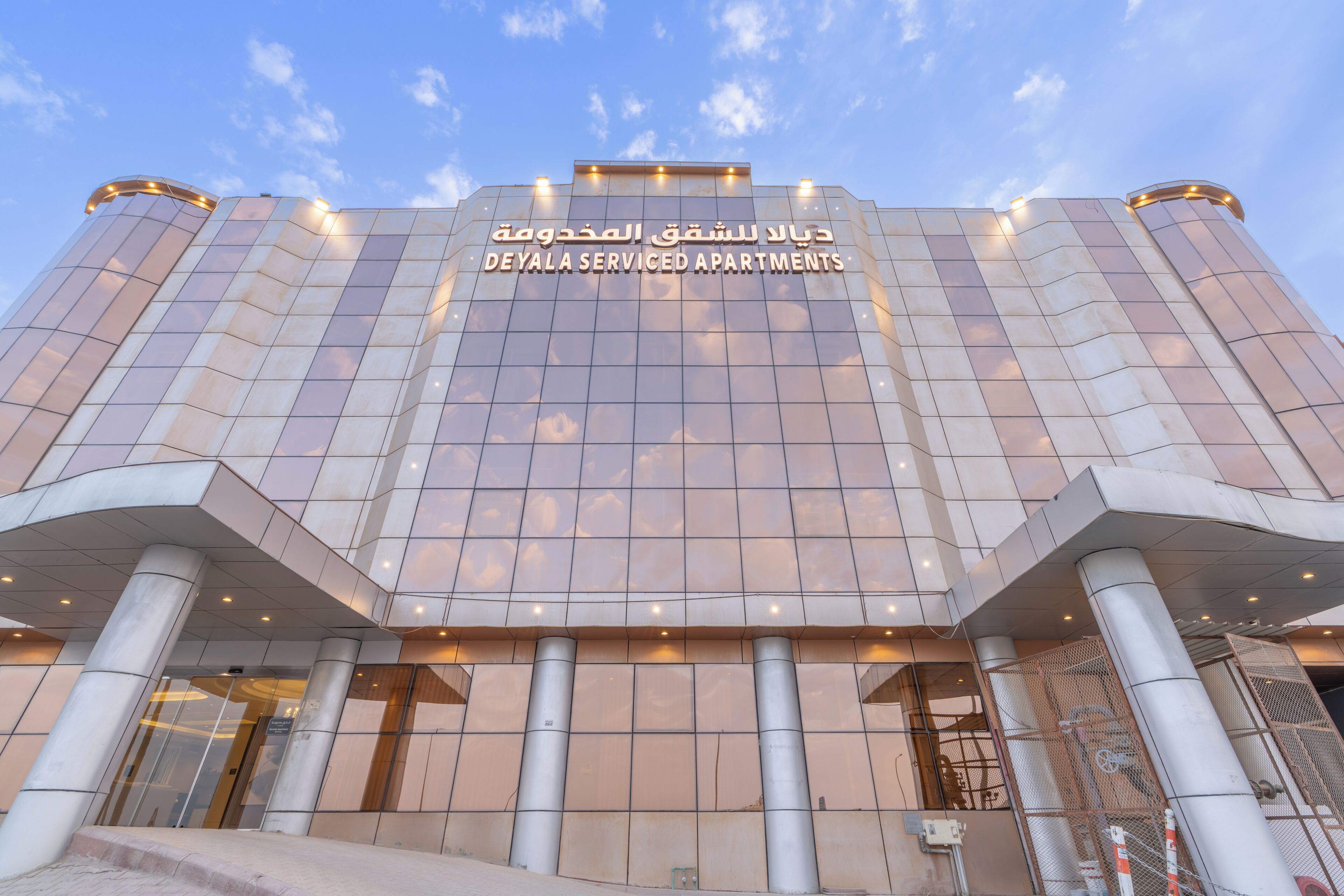 Un immeuble moderne avec une façade en verre et une enseigne indiquant « DÉYALA SERVICED APARTMENTS ».