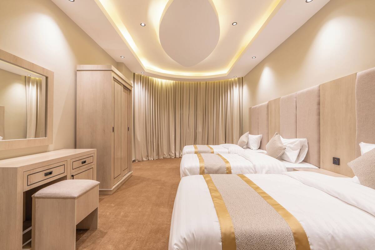 A hotel room with a large bed, a bedside table, a mirror, and a wardrobe.