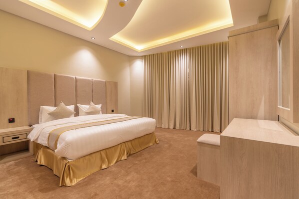 Una habitación de hotel moderna con una cama grande, cabecera de madera, mesita de noche y un banco integrado.