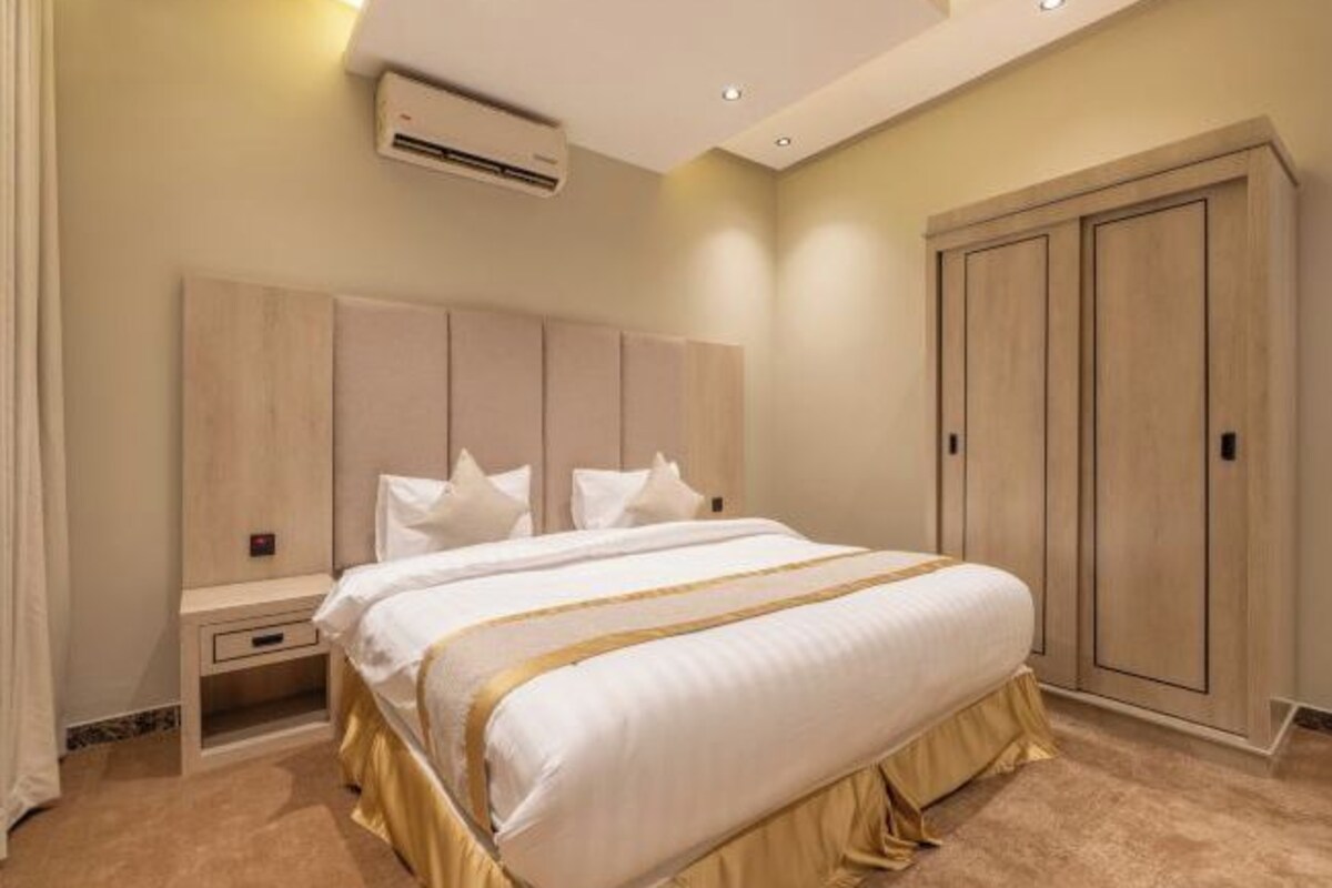 Une chambre à coucher comprenant un lit, des tables de chevet, un appareil de climatisation et une armoire.