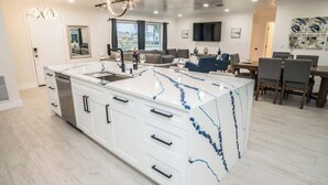 A modern kitchen with a large island, white cabinetry, and a marble countertop. - Waterfront | Dock, Htd Pool, Hot Tub & Game Room (Apollo Beach)