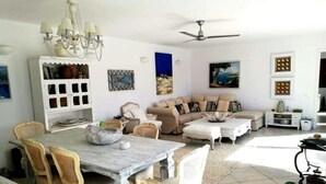 Uma sala de estar espaçosa com uma mesa de jantar, cadeiras, um sofá e um ventilador de teto.
