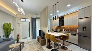 A modern kitchen with a built-in refrigerator, a dining area with a table and chairs, and a living room with a sofa and a coffee table. - Modern Muse Two-Bedroom Apartment (Thessaloniki)