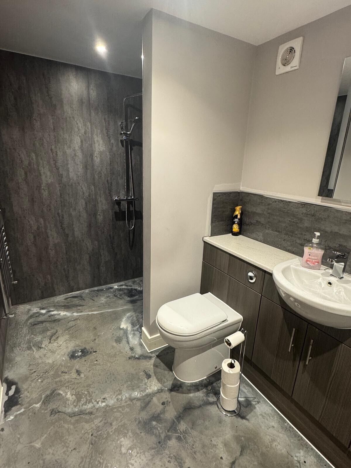 A modern bathroom with a shower, toilet, and sink.