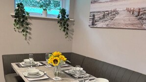 Un espace repas avec une table rectangulaire dressée pour six personnes, entourée de bancs rembourrés.