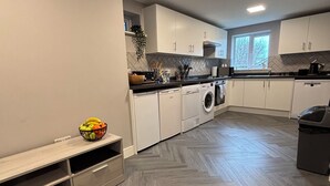 Une cuisine moderne avec des meubles blancs, un parquet en bois disposé en chevrons et un lave-vaisselle encastré.