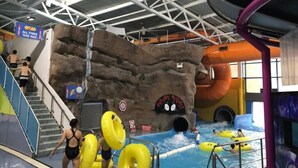 Un parc aquatique intérieur doté d’un mur d’escalade, de toboggans et de bouées gonflables.