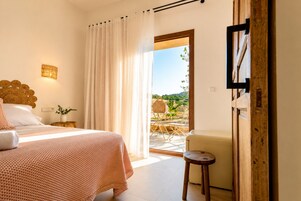 Quarto com cama, mesa de cabeceira, luminária, cadeira e vista para o exterior.