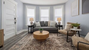 A living room with a gray sofa, two side tables with lamps, a round coffee table, and a patterned rug.