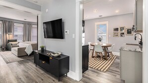 A modern living room with a sofa, a black entertainment unit, and a flat-screen TV. - Remodeled, Washer, Dryer, Mins to Beach & Downtown (Michigan City)