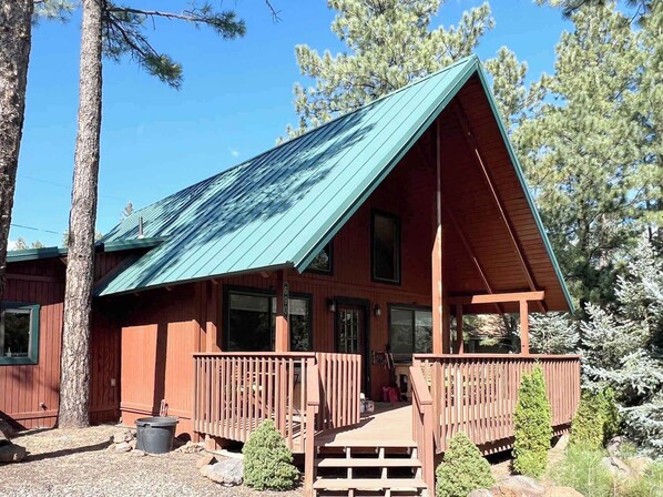 Eine Holzhütte mit einem grünen Metalldach und einer Veranda mit Geländern.