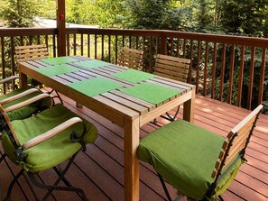 Une terrasse en bois avec une table et des chaises, entourée d’une rambarde.