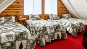 A bedroom with two beds, a wooden ceiling, and large windows.