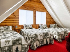 Un dormitorio con dos camas, techo de madera y ventanas amplias.