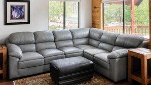 A spacious living room with a large L-shaped sectional sofa, a wooden coffee table, and a ceiling fan.
