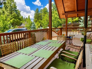 Een terras buiten met een houten tafel en stoelen, omringd door een houten balustrade.