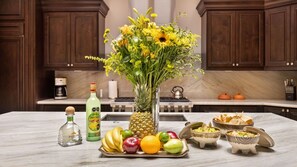 A kitchen counter with a pineapple, fruits, a bottle of Jose Cuervo tequila, and bowls of food. - Luxury Oceanfront Diamante Condo (Cabo San Lucas)