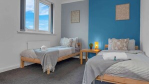 Un dormitorio con dos camas, una ventana, un radiador y obras de arte en las paredes.