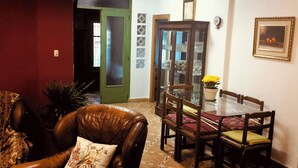 A dining area with a glass table, wooden chairs, and a green door leading to another room.