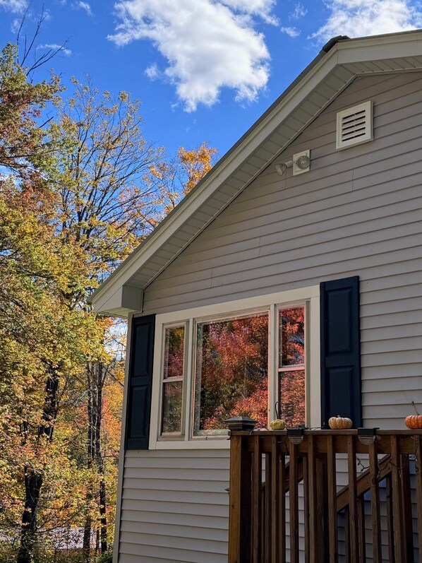 A house with a gabled roof, a front porch with a railing, and a window with shutters.