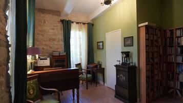 Une pièce comprenant un bureau en bois, une chaise, une bibliothèque, un tapis à motifs et un lustre.