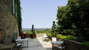 A stone patio with outdoor furniture, a barbecue grill, and a view of the countryside. - Chambres d'hôtes La Gourguille (Barjac)