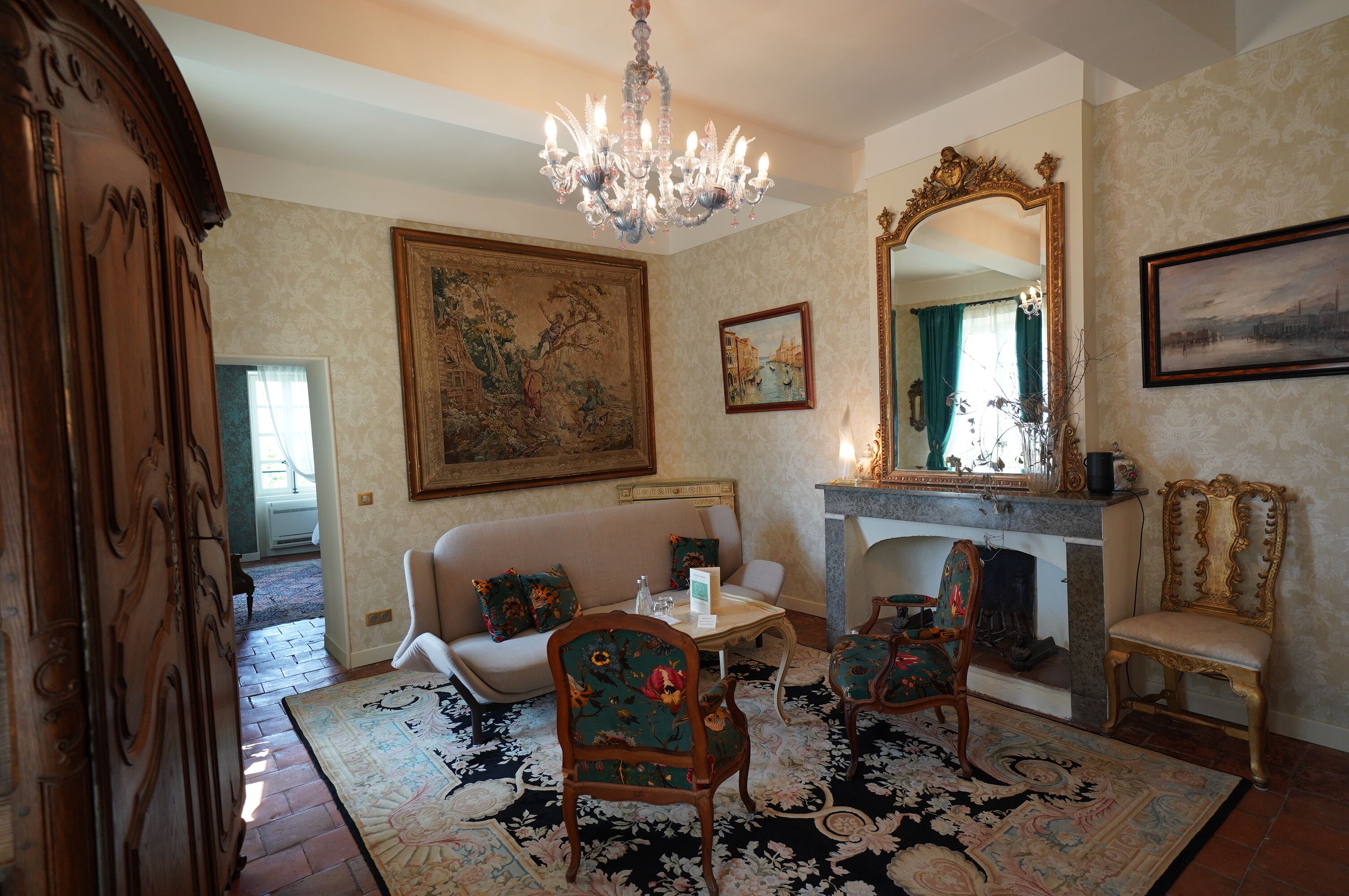 Een klassieke kamer met een open haard, gedetailleerd meubilair en een kroonluchter.