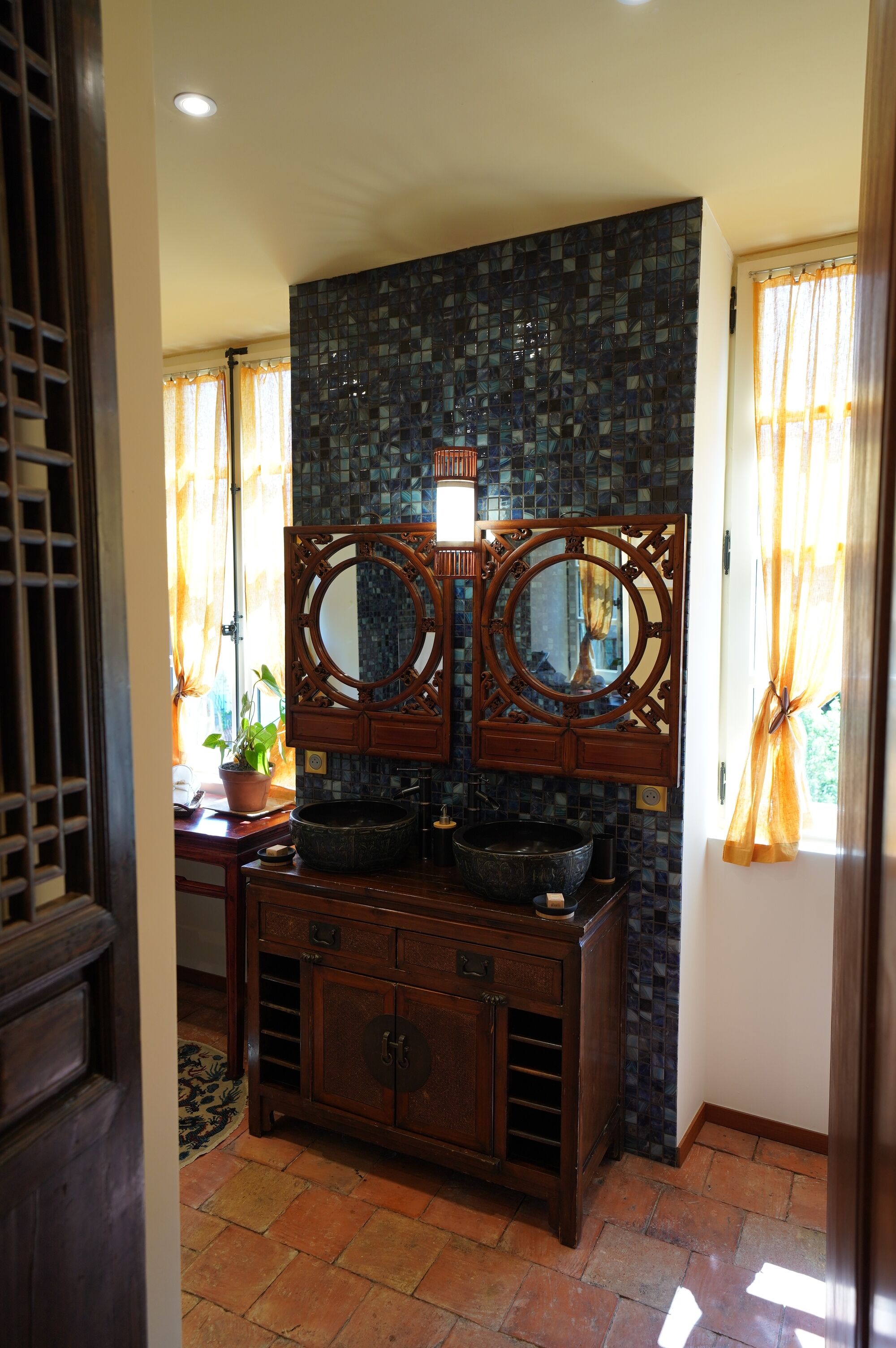 Une salle de bain avec un grand miroir, un lavabo et un mur recouvert de carreaux.