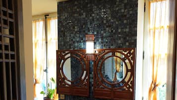 Une salle de bain avec un grand miroir, un lavabo et un mur recouvert de carreaux.