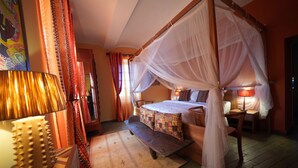 A four-poster bed with a canopy, a bench, a bedside table with a lamp, and a patterned rug. - Chambres d'hôtes La Gourguille (Barjac)