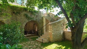 A stone staircase leading up to a small stone building with a metal railing, surrounded by greenery and an archway. - Chambres d'hôtes La Gourguille (Barjac)