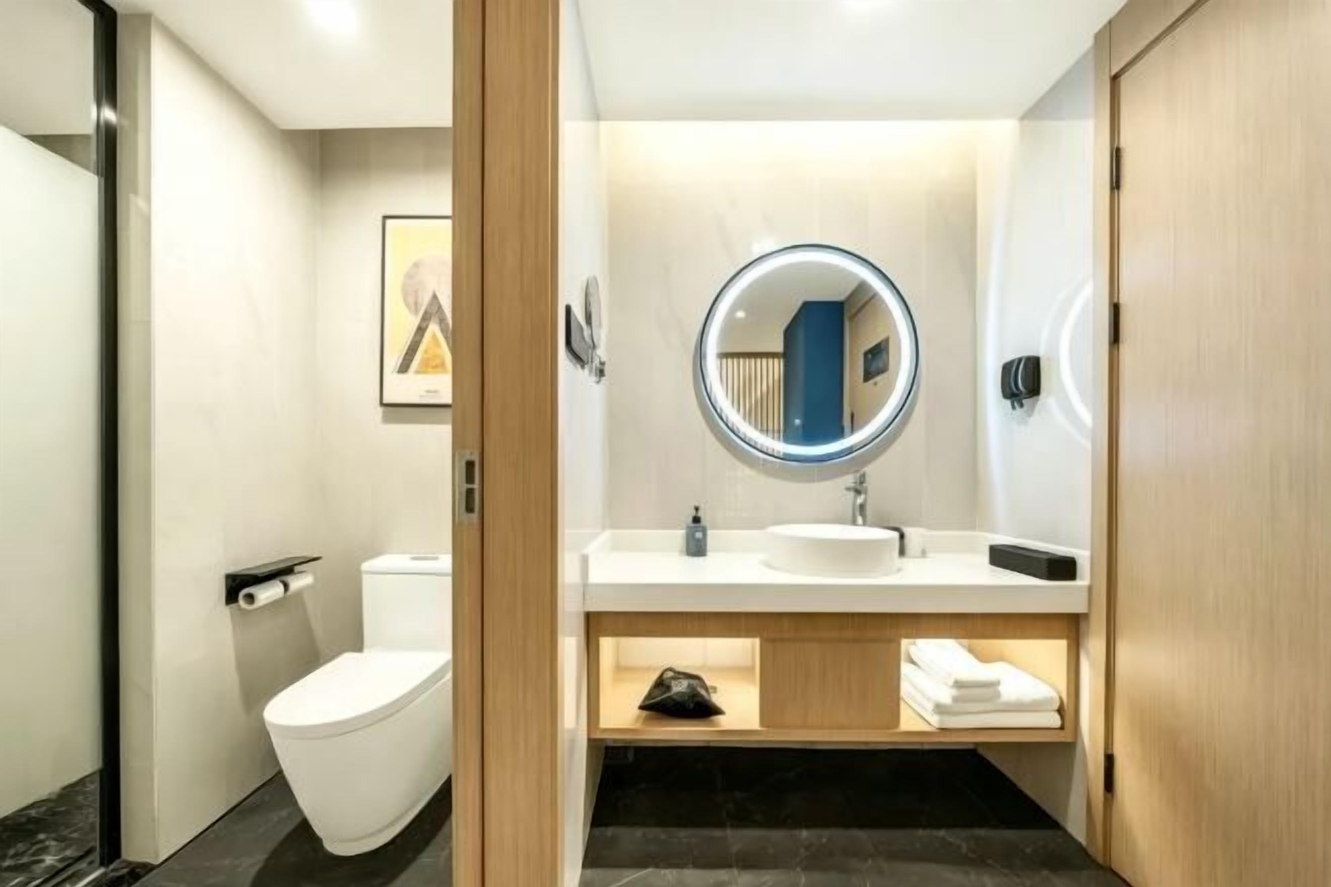 A modern bathroom with a toilet, sink, and mirror.