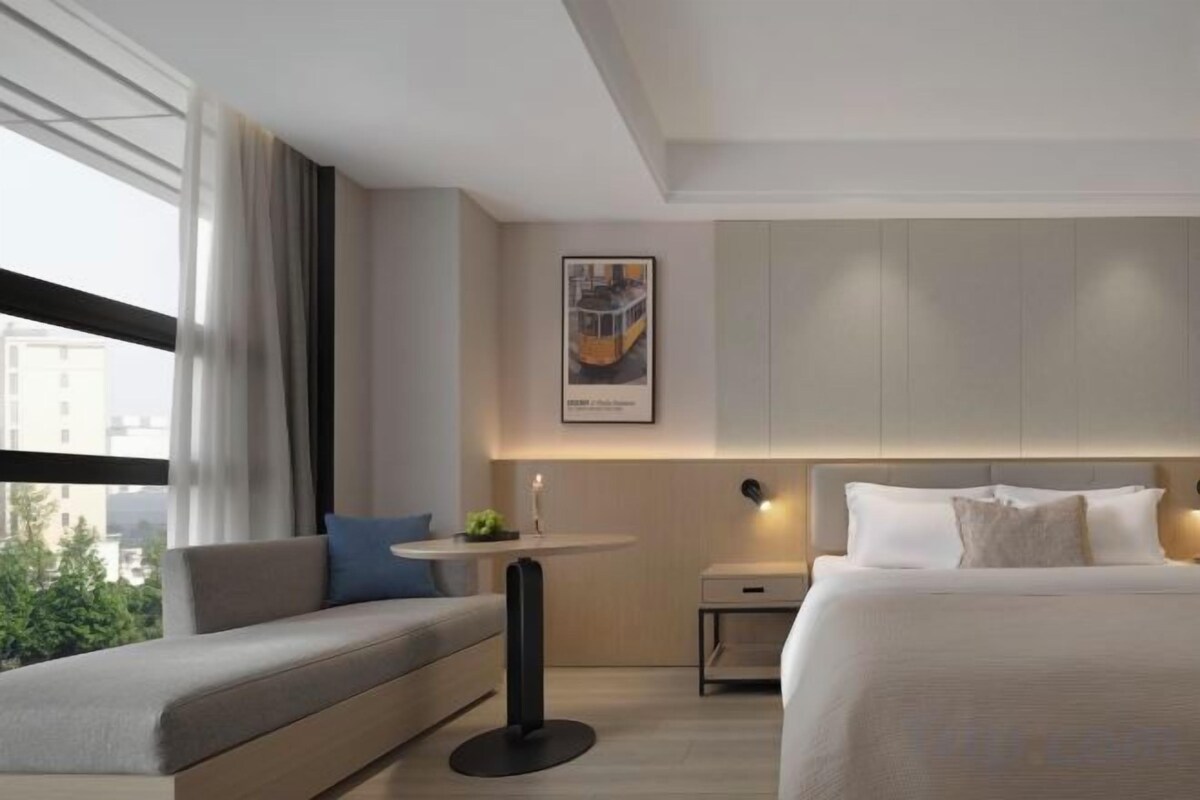 Una habitación de hotel moderna con una cama, un sofá, una mesita y una mesita de noche.