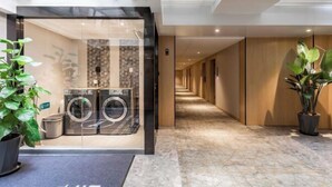 A hotel lobby with a glass-walled laundry area, a marble floor, and potted plants. - Anting Hotel (Chongqing Guanyinqiao Hongqihegou Subway Station) (Chongqing)