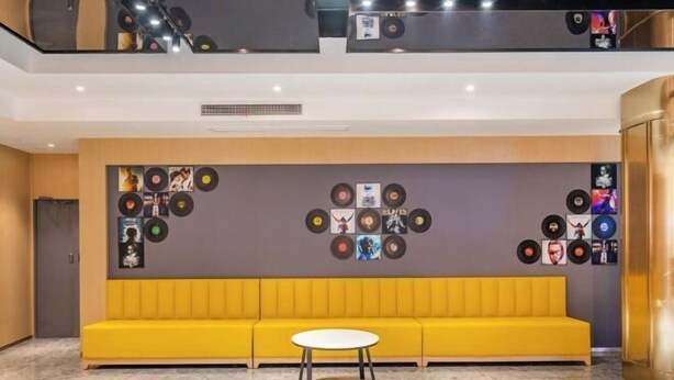 Ein modernes Interieur mit einem gelben Sofa, einem runden Tisch und einer Wand, die mit Schallplatten verziert ist.