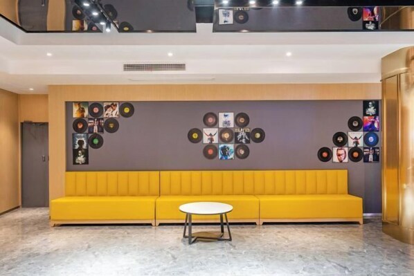 A modern interior with a yellow sofa, a round table, and a wall decorated with vinyl records. - Anting Hotel (Chongqing Guanyinqiao Hongqihegou Subway Station) (Chongqing)