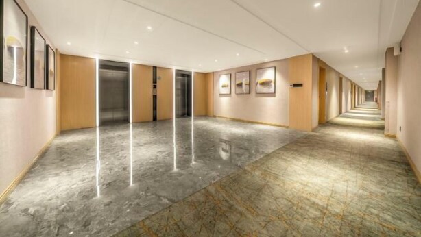 A long, well-lit hallway with marble flooring and framed artwork on the walls. - Anting Hotel (Chongqing Guanyinqiao Hongqihegou Subway Station) (Chongqing)