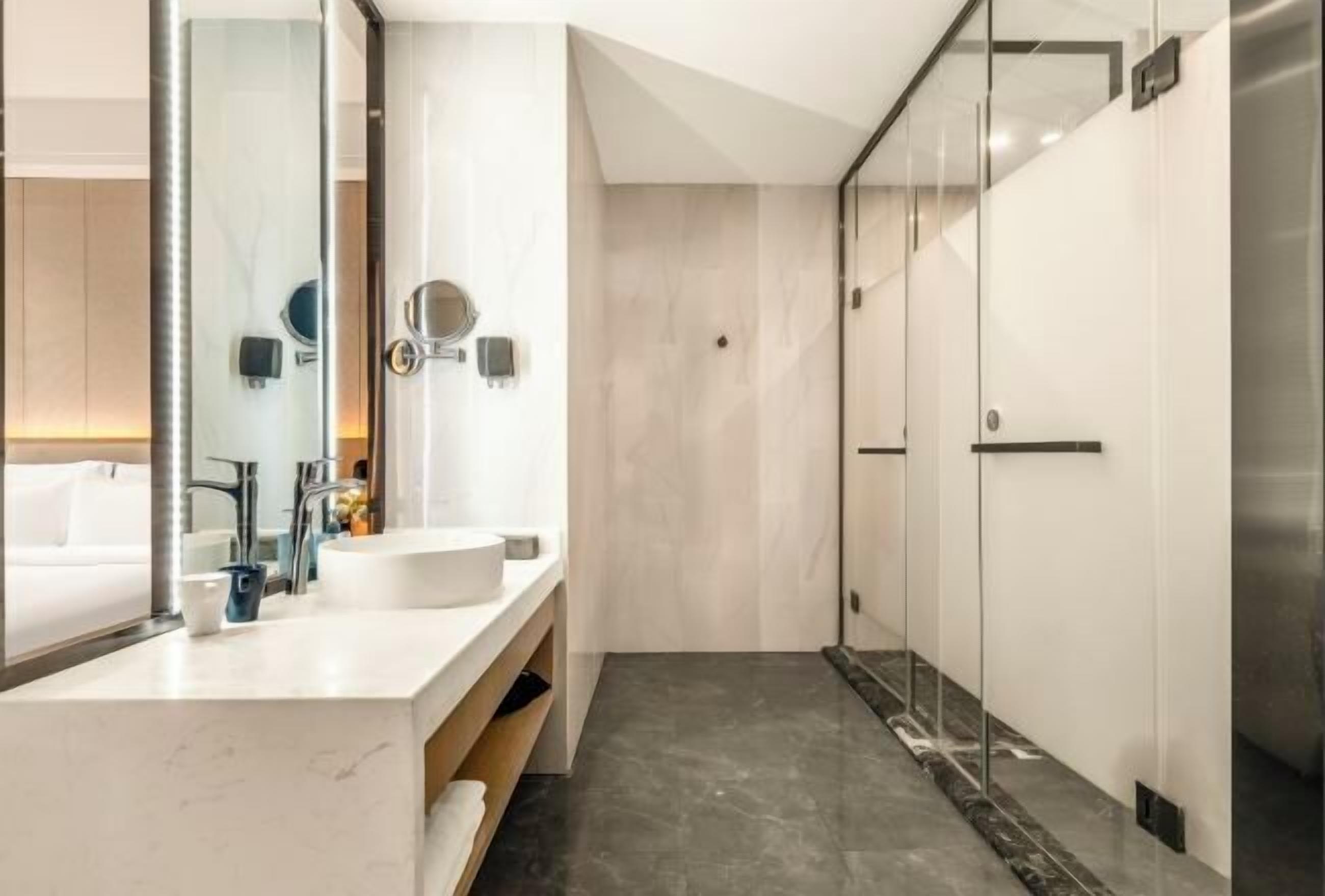 A modern bathroom with a large mirror, a white sink, and a glass shower enclosure.