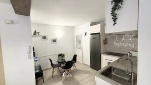 A compact kitchen with a dining area, a refrigerator, and a sink.