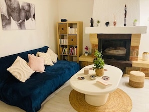A living room with a blue sofa, a white coffee table, a bookshelf, and a fireplace.