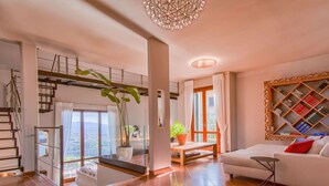 A spacious living area with a staircase, a large window offering a city view, a bookshelf, and a cozy sofa. - Wonderful private villa for 9 guests with WIFI, A/C, private pool, TV and balcony (Montecatini Terme)