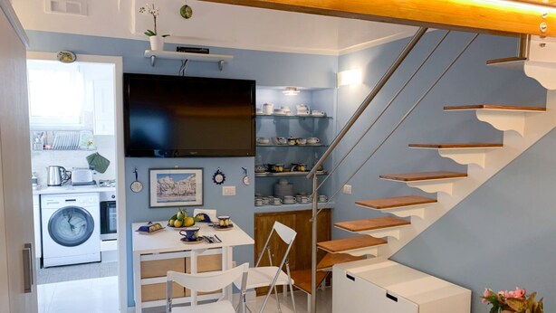 Uma cozinha compacta com máquina de lavar, sala de jantar com mesa e cadeiras, e escada com degraus de madeira.