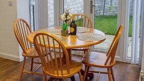A dining area with a round table, four wooden chairs, a bottle, and a vase of flowers. - Modern Main Door Flat Edinburgh City Center (Edinburgh)