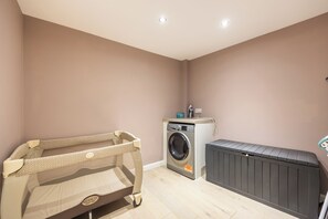 A laundry room with a washing machine, a drying rack, and a baby changing station.